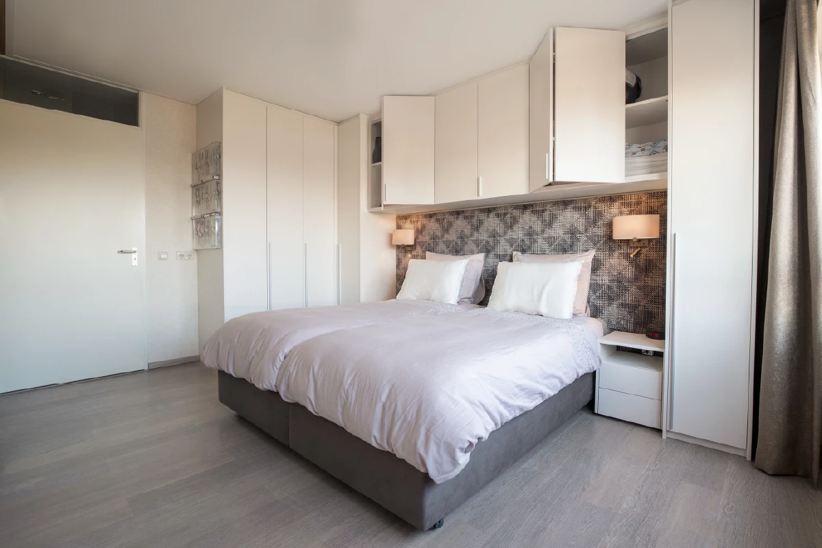 Bed met kastombouw, de deuren boven het bed geopend